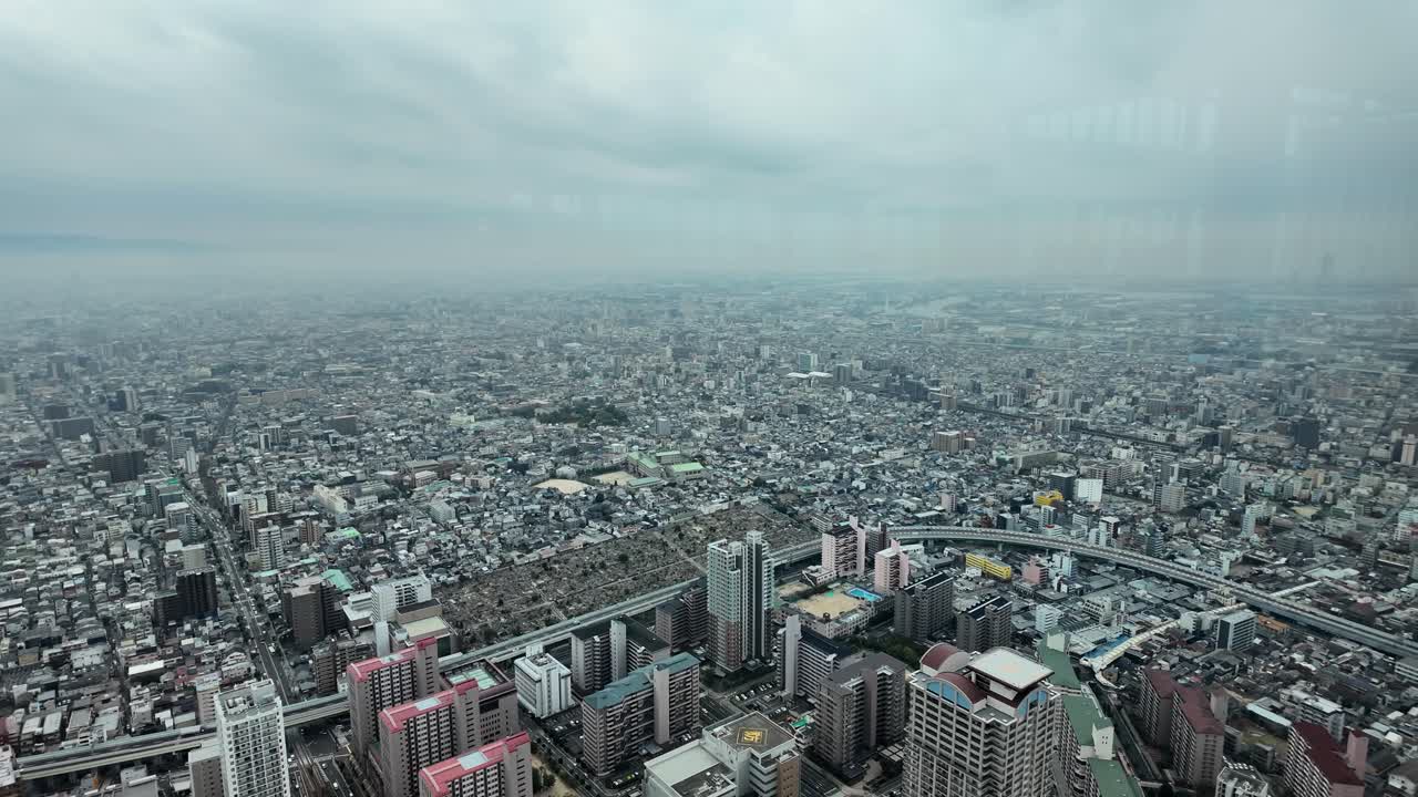Overlooking Osaka cityscape with buildings, roads, and urban development under a cloudy sky