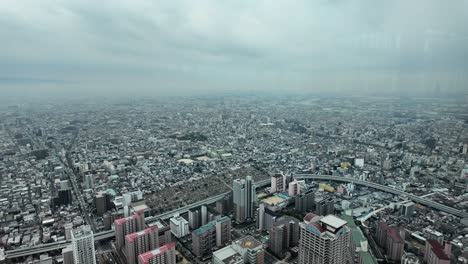 overlooking osaka cityscape with buildings, roads, and urban development under a cloudy sky