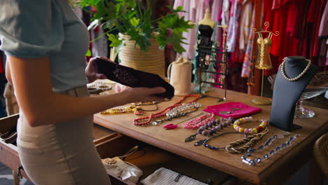 mujer en una tienda de ropa de moda comprando accesorios o arreglando la exhibición
