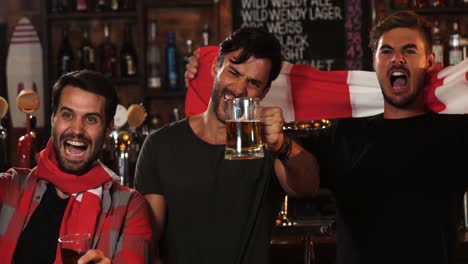 group of friends watching tv in bar