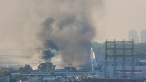 fire trucks mounted with an aerial tower throwing water on a fire in a factory complex