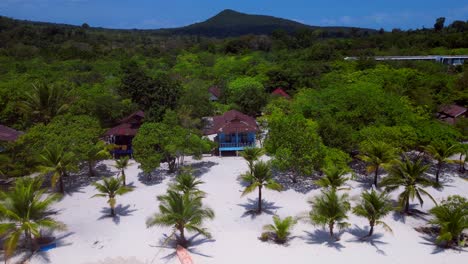 tropical hut on white sand beach meeting calm turquoise water in koh rong island, cambodia. stunning aerial view flight fly reverse drone