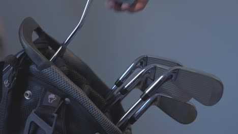 golfer removing a putter from a bag with a selection of irons remaining