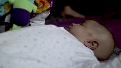 adorable bebé indio de 2 meses acostado de espaldas sosteniendo un colorido juguete de peluche