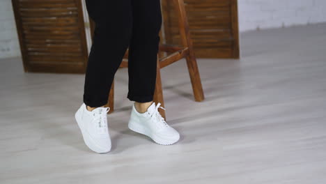 woman wearing black trousers dances in white sneakers. new fashionable footwear demonstration concept.