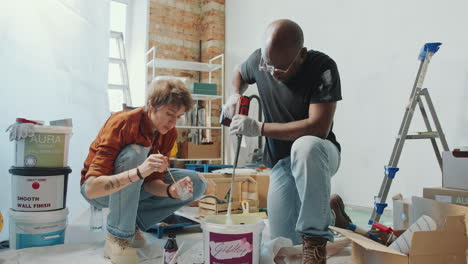 couple stirring paint and colourant with drill during home renovation