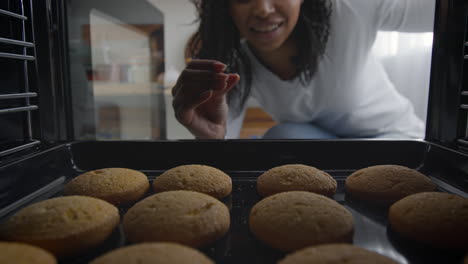 woman checking cookies in oven