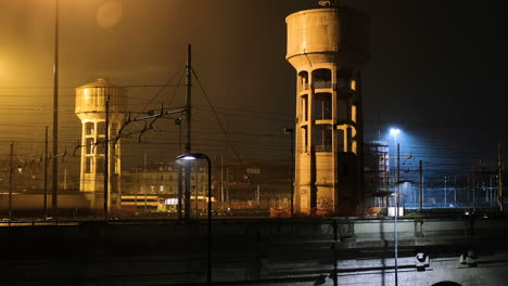 timelapse of trains passing by on rainy night in milan, italy