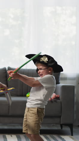 toddler and preschooler play with toy swords at home. girl with long braids and boy wearing pirate costume play duel in living room