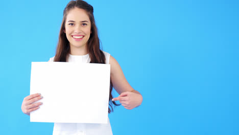 hermosa mujer sosteniendo un cartel en blanco sobre un fondo azul