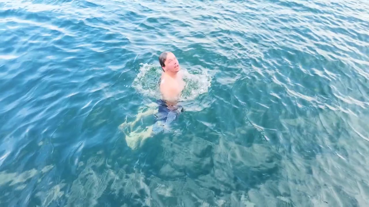 Giovane uomo nuota sott'acqua al rallentatore.