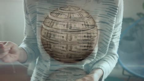 digital composite video of globe made of american dollar bills against woman sewing face mask