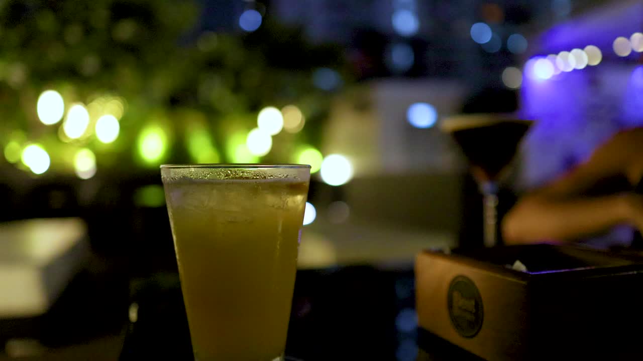 Woman drinks cocktail at rooftop bar, city lights bokeh, low light, shallow depth of field