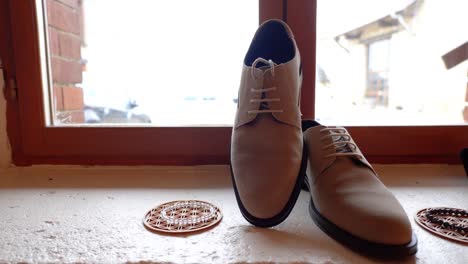 beige suede oxfords and accessories on a window sill