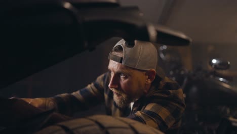 Close-up-of-a-mechanic-guy-in-a-checkered-shirt-repairing-a-motorcycle-in-a-studio-workshop-during-a-working-day