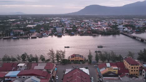 kampot-stadt, aufnahme eines drohnenlifts auf dem alten markt mit blick auf den bokor-hügel und fischerboote, die entlang des flusses fahren