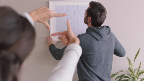 una joven pareja se muda a una nueva casa. los propietarios cuelgan fotos decorando la casa juntos disfrutando de una mudanza exitosa en el apartamento.