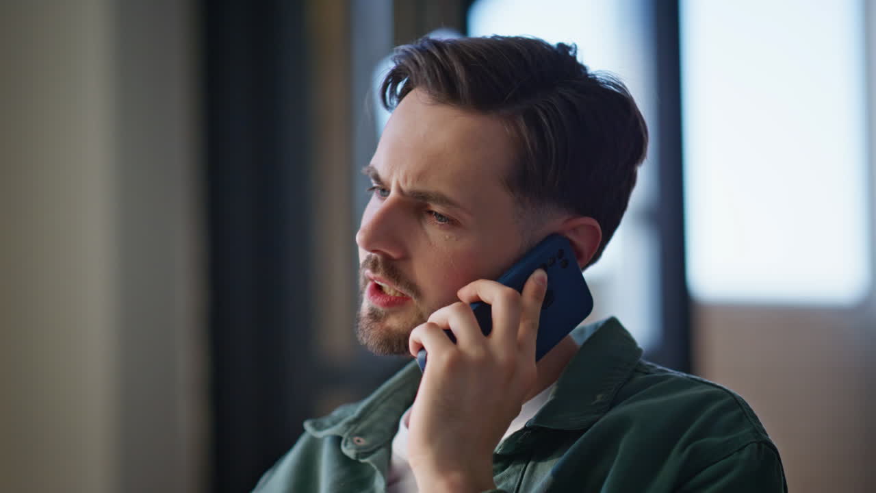 Annoyed guy calling mobile phone relaxing at home couch. Tensed man talking