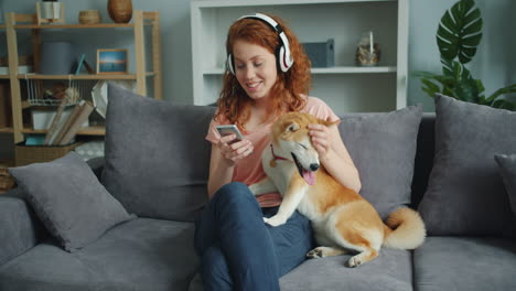 woman listening to music with shiba inu dog on sofa
