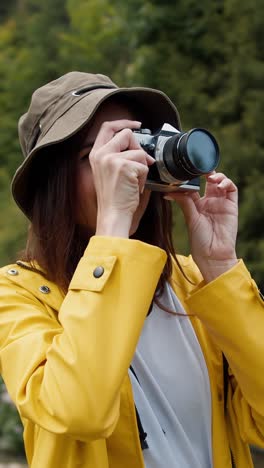 woman taking pictures outdoors in a yellow raincoat