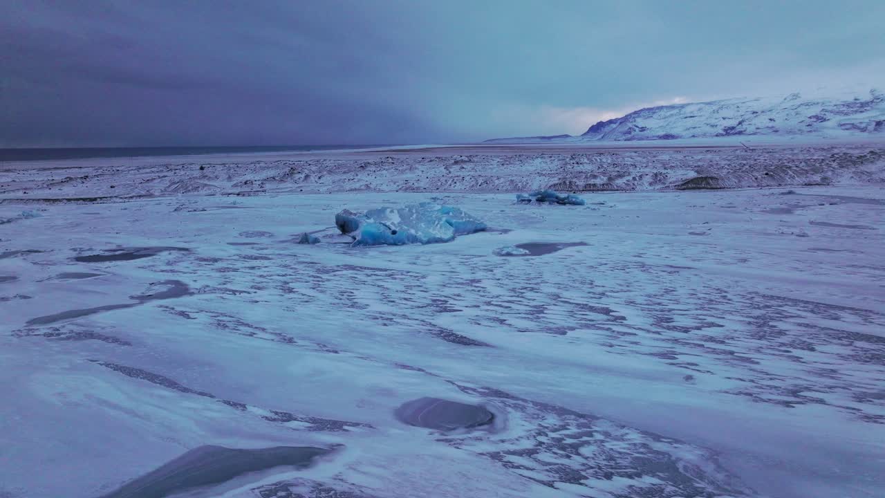 Aerial panoramic view over the frozen Jokulsarl&oacute;n lake area, with icebergs covered in snow, in Iceland, at dusk