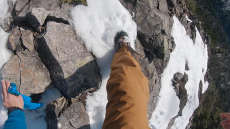 a man climbing a steep mountain rock by hand