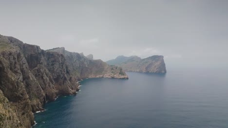 Flying-near-steep-rugged-limestone-coastal-mountain-range,-Mallorca