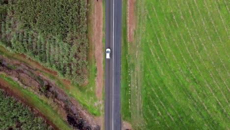 aerial pan up reveal from moving car on highway in cairns surrounded by farmlands