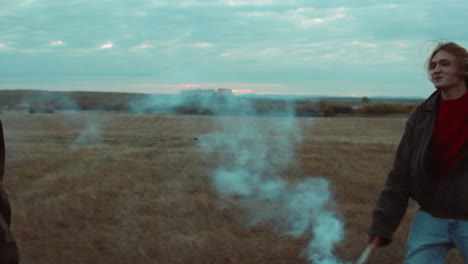 couple walking with smoke bomb on autumn field