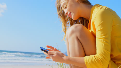 Vista-Lateral-De-Una-Joven-Caucásica-Usando-Un-Teléfono-Móvil-En-La-Playa-4k