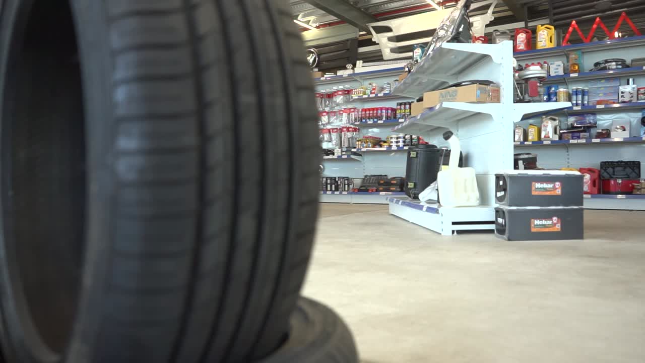 Pristine tire selection prominently framing blurred automotive parts store interior, highlighting retail inventory and product range
