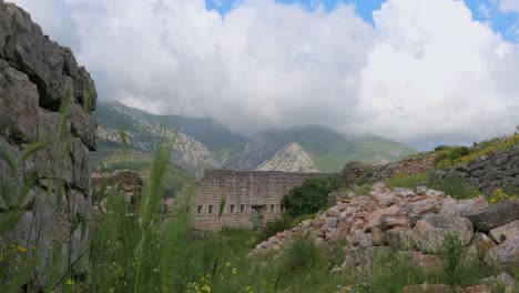 stunning view of old fortress and ruins by the mountains with dramatic clouds