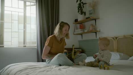 madre y bebé jugando con dinosaurios en el dormitorio