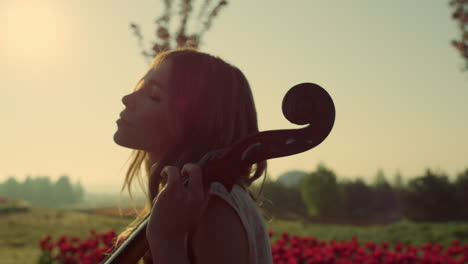 relaxed girl enjoying performance in sunlight. young woman embacing contrabass.