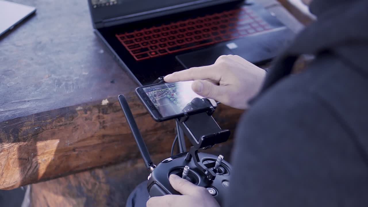 piloto de avión no tripulado que opera el control remoto con teléfono inteligente y portátil