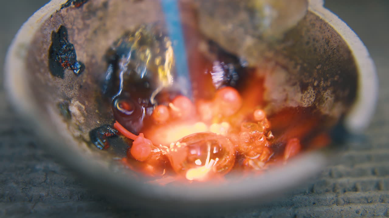 fundición de oro en taza pequeña con quemador caliente en el taller cerca