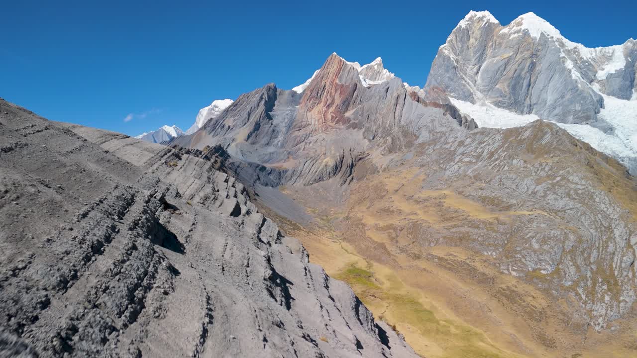Fast aerial forward shot flying close to a rugged mountain ridge, revealing jagged peaks and epic glacial terrain on the Huayhuash trek in Peru's Andes