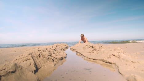 Young-boy-is-digging-a-path-into-the-sand-at-the-beach