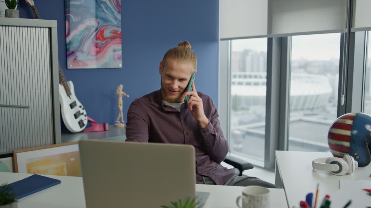 Nærbillede af grinende fyr, der chatter i mobiltelefon på kontoret. Startupper har en telefonsamtale.
