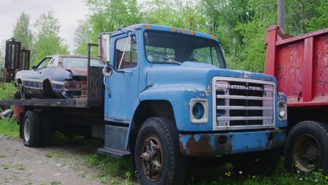 A-Vintage-International-Truck-rusting-away-with-a-Ford-Torino-from-the-1970s-sitting-on-its-flatbed-surrounded-by-other-scrap-cars