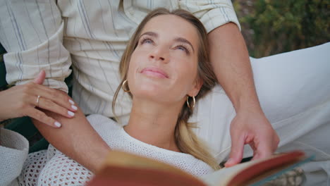 serene woman laying boyfriend knees bench park closeup. man hands holding book