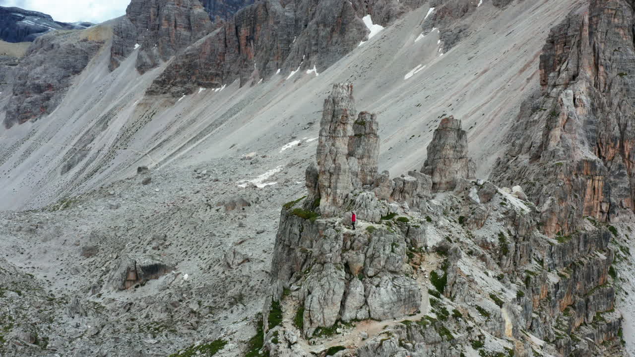 hombre escalando acantilados dolomitas con chaqueta roja, italia