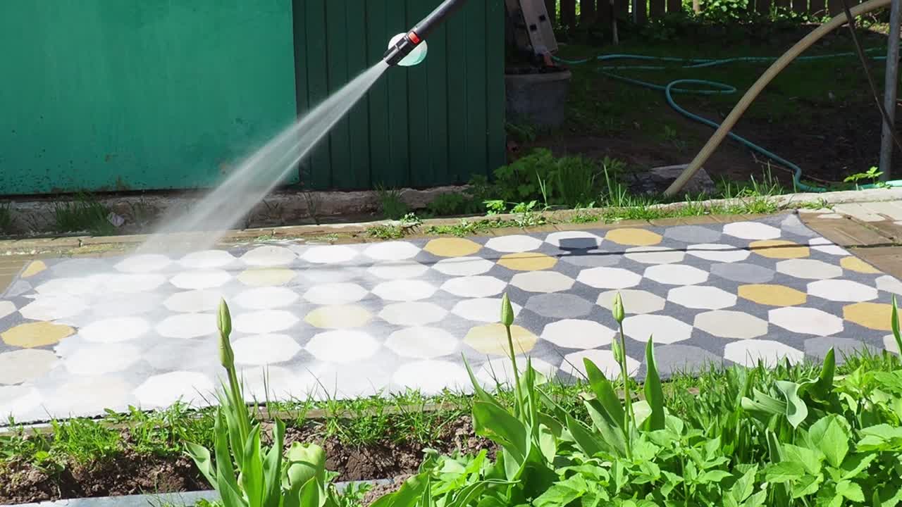 man washing carpet with pressure washer outdoors
