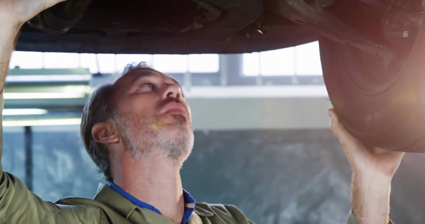 Animation of shapes over caucasian male mechanic reapiring car