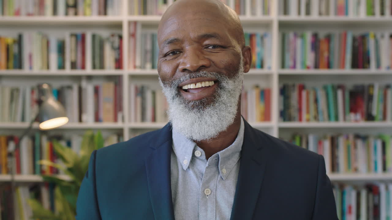 ritratto ravvicinato di un uomo d'affari afroamericano anziano con la barba sorridente sicuro di sé che gode di una carriera di successo pietra miliare professionale maschio nero maturo che indossa un abito in biblioteca
