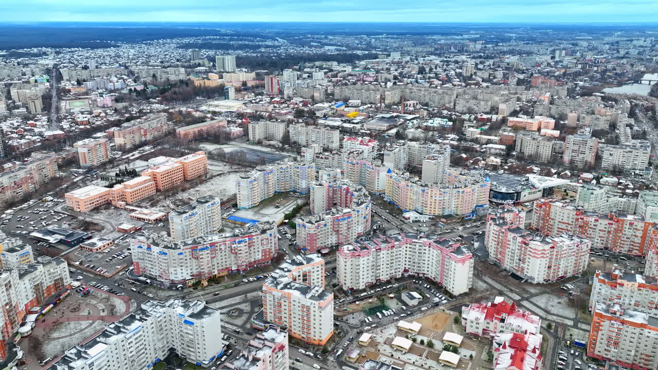 Large blocks of flats, roads and cars in residential area. Rise over the beautiful site of the big city. Cityscape and nature at the backdrop of grey winter sky.