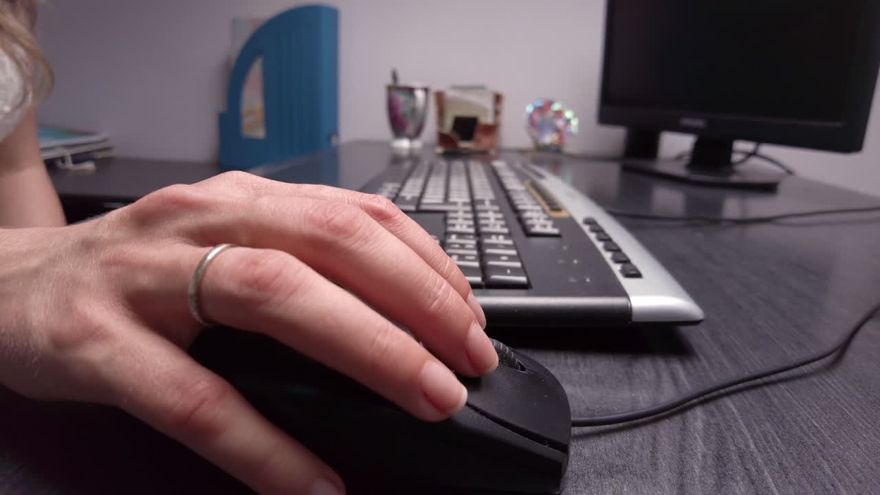 Close up of a woman clicking on a mouse while working on a computer