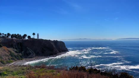 still video of waves hitting the beach on the cliffs of rancho palos verdes with a lighthouse and catalina island in the background