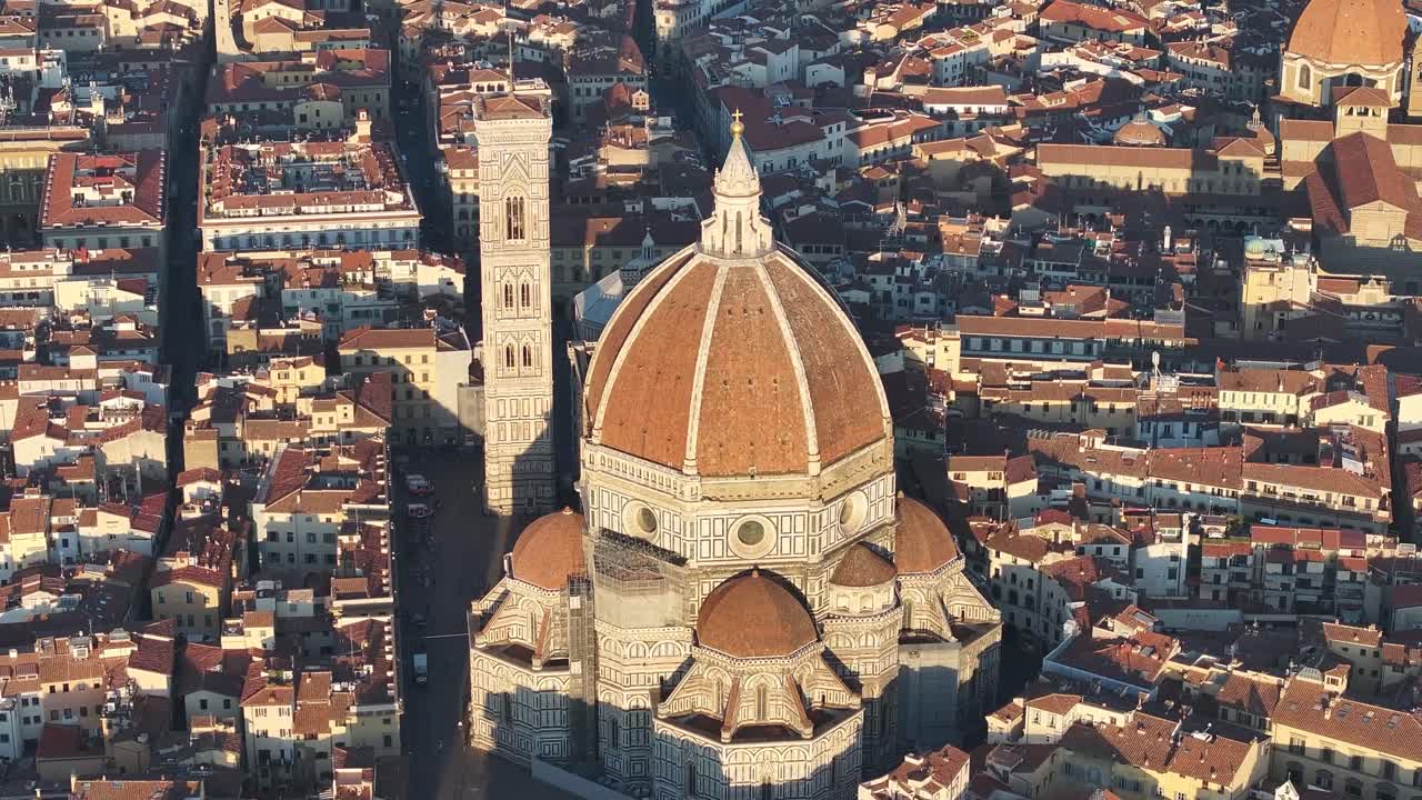 Close-up vertical aerial drone view of the Florence Duomo, or Florence Cathedral, and Giotto's Campanile surrounded by historic city rooftops at sunrise