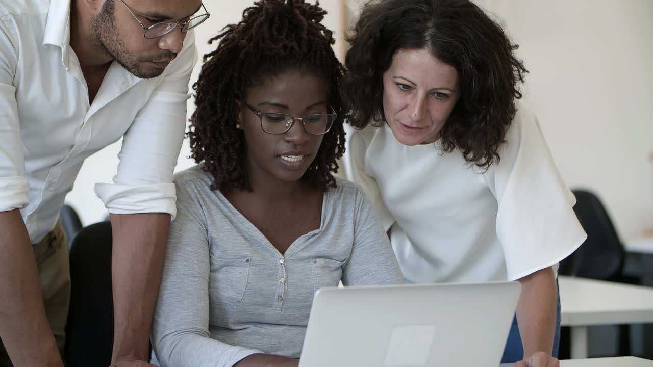 Responsible workers talking and looking at laptop.